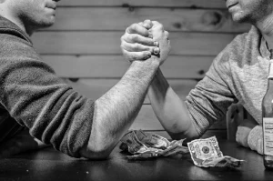 Black and white photo of two men arm wrestling over cash