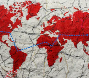 A red world map on old crinkled with a journey mapped by a blue dashed line