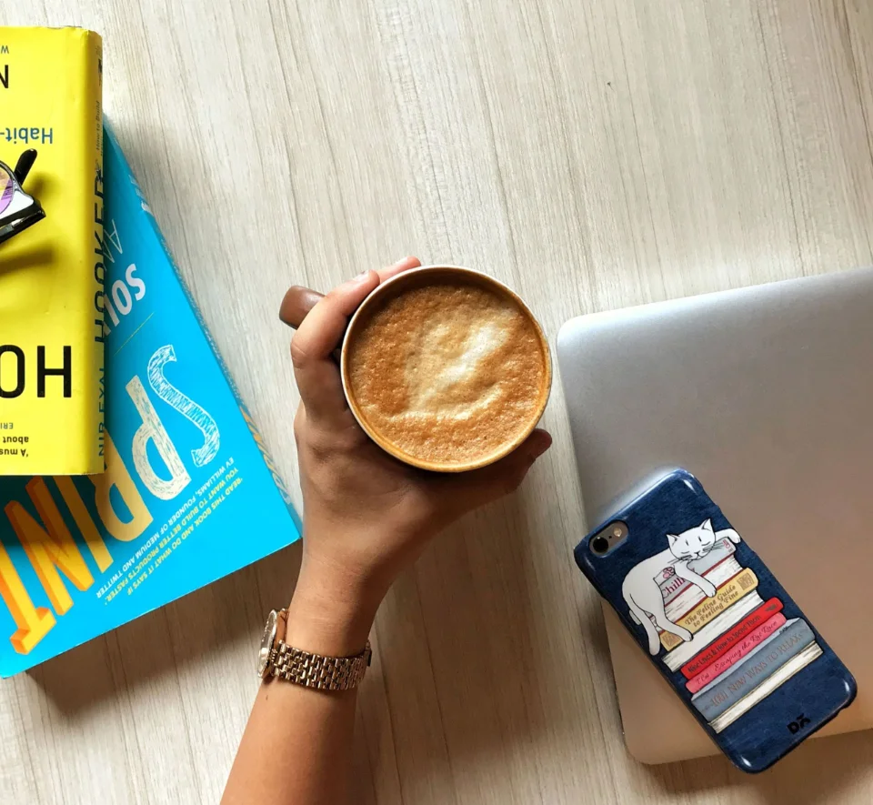 From Pexels by Vadodara, GJ, India hand holding a latte over the books "Sprint" and "Hooked"
