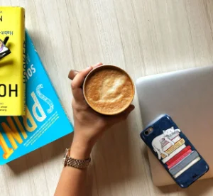 hand holding a latte over the books "Sprint" and "Hooked"