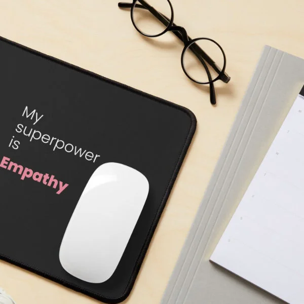 A mouse pad with the phrase "My superpower is empathy" in white and pink letters.