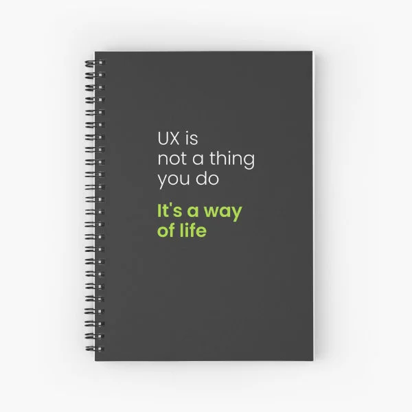 A spiral notebook with the phrase "UX is not a thing you do, it&rsquo;s a way of life" in white and green letters.