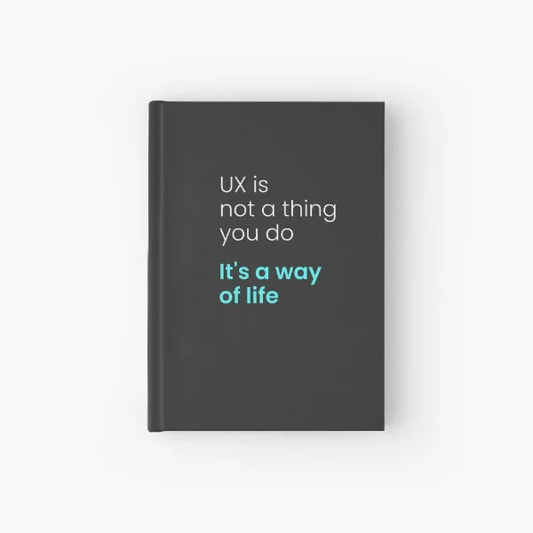 A hardcover journal with the phrase "UX is not a thing you do, it&rsquo;s a way of life" in white and turquoise letters.