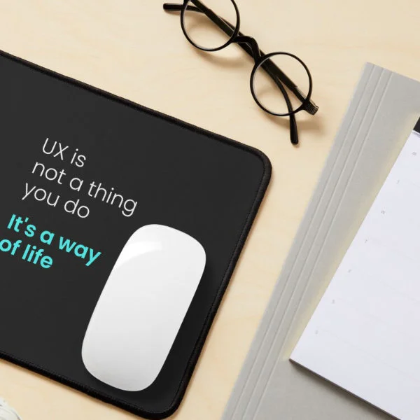 A mouse pad with the phrase "UX is not a thing you do, it&rsquo;s a way of life" in white and turquoise letters.